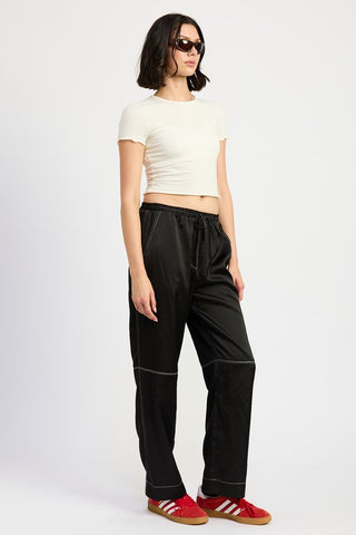 side view black satin wide leg pants showing contrast stitch at side seam profile and drawstring waist from side