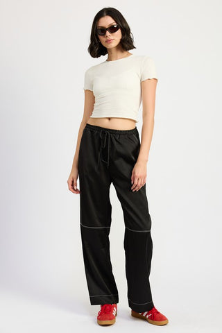 three quarter view black contrast stitch satin wide leg pants showing white topstitching detail and relaxed leg silhouette