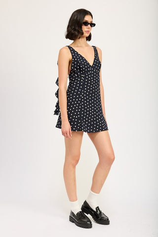 back view black polka dot ruffle mini dress showing back construction and cascade side ruffle panels from behind
