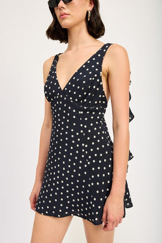 three quarter view black polka dot cascade ruffle mini dress showing deep V-neck and side ruffle panels with flared skirt