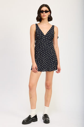 full length front view black polka dot ruffle mini dress showing deep V neckline, side ruffles and mid-thigh hem