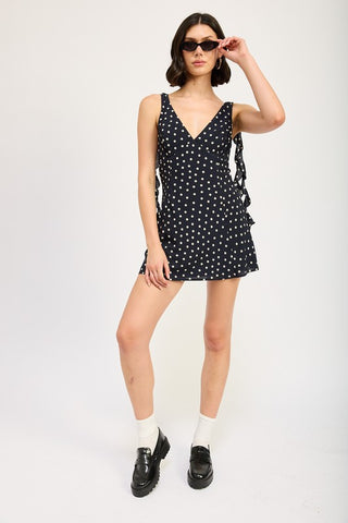 side view black polka dot ruffle mini dress showing cascade side ruffle profile and A-line skirt silhouette