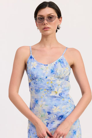 three quarter view blue watercolor floral satin slip midi dress showing side ruching at waist and fluid midi length