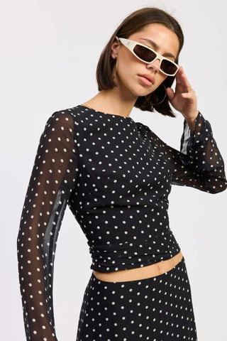 full length model in black polka dot bell sleeve sheer crop top showing dramatic sleeve length and crop hem