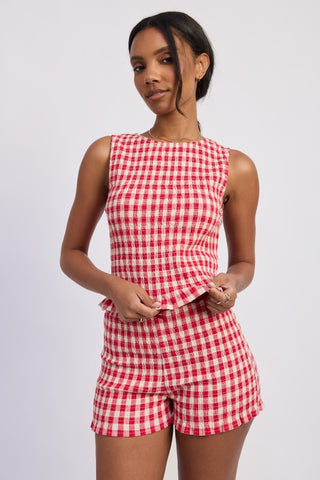 resort pose model in blue gingham smocked shorts showing lettuce hem shorts and co-ord set styling