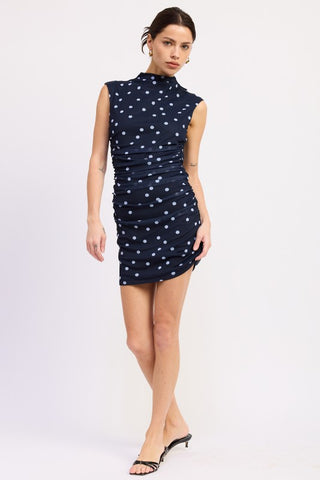 three-quarter view navy blue mock neck polka dot mini dress showing ruched side panels and above knee length
