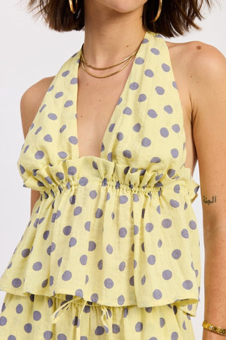detail shot yellow gray polka dot halter top showing deep V-neck depth and elasticized ruffle peplum waist
