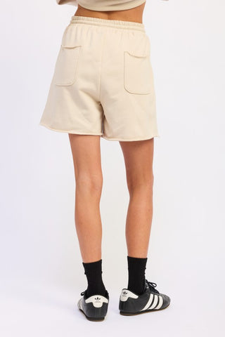 three-quarter view cream cotton French terry shorts showing side pocket and drawstring waist detail