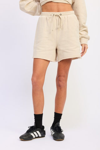 full length model in cream French terry shorts showing mid-thigh length and relaxed fit