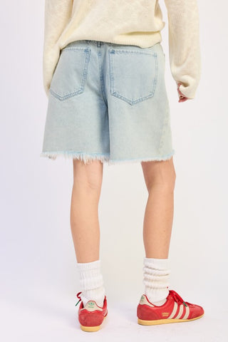 editorial styling light wash distressed denim bermuda shorts with cream knit top white socks and sneakers