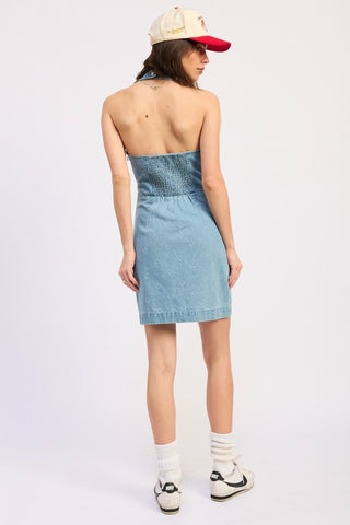 editorial pose model in Camille denim halter mini dress showing deep V neck and heart snap hardware full look