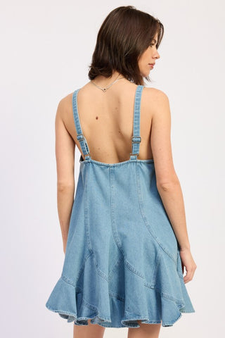 three quarter back angle light blue denim paneled overall mini dress showing full silhouette and ruffle hem detail