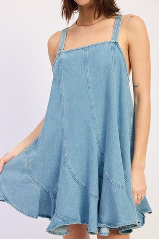 close up bodice light blue denim overall dress showing square neck thick straps and diagonal panel skirt construction