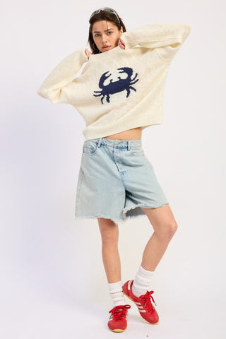 three quarter view cream crab intarsia graphic knit sweater showing boxy silhouette long sleeves and navy crab motif