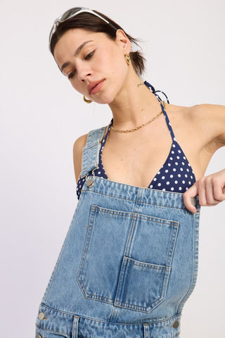 portrait close up model in denim barrel overall showing square bib neckline gold chain and buckle strap detail