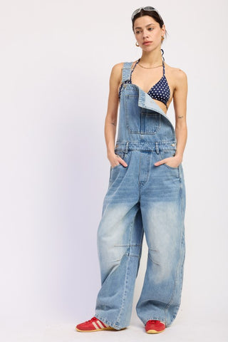 model in denim barrel overall with one strap unhooked showing side button closure and full barrel leg width