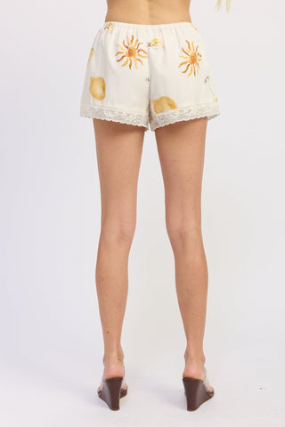 White lace shorts with sunflower pattern worn by a person on a white background