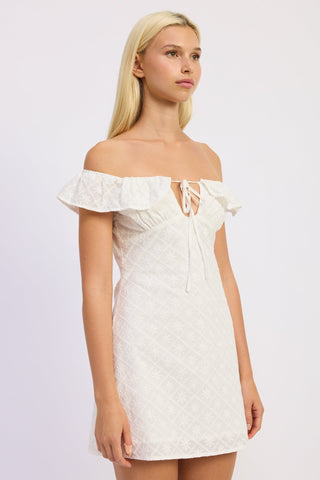 Woman wearing a white off-shoulder dress on a plain background
