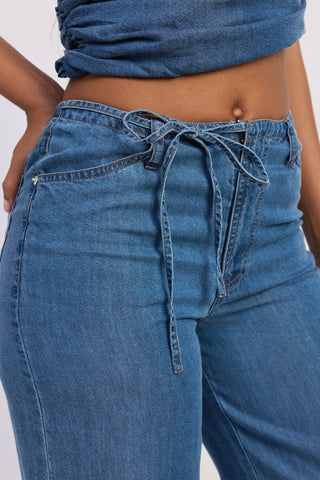 Blue jeans with a tie-waist design on a white background