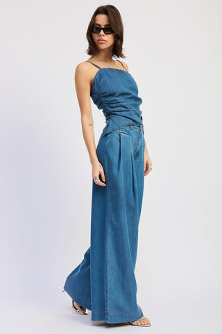 Woman wearing a blue denim jumpsuit on a white background