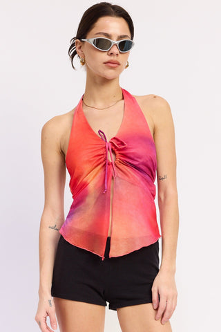 Woman wearing a colorful halter top and black shorts on a white background