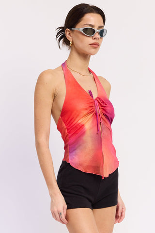 Woman wearing a colorful tie-dye top and black shorts on a white background