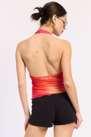 Woman wearing a red halter top and black shorts on a white background