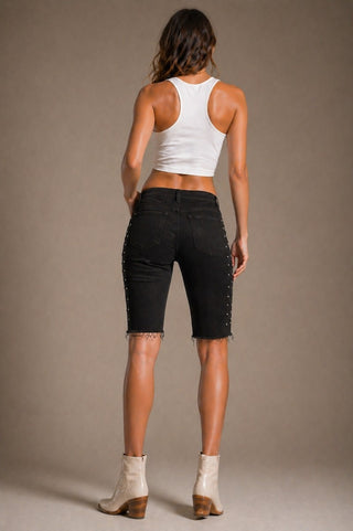 Side view low rise capri jeans frayed hem stud detail outer seam black denim
