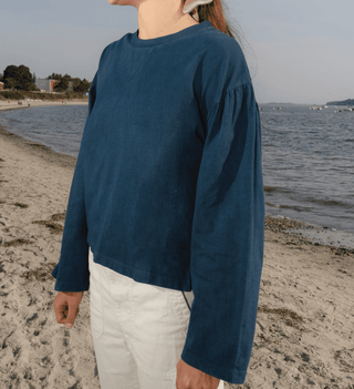 Person wearing a blue long-sleeve shirt on a beach