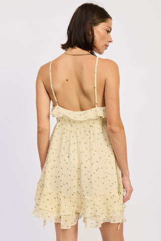 Woman wearing a light yellow romper with thin straps on a white background