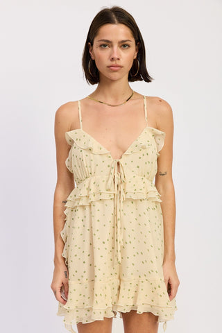 Woman wearing a light yellow polka dot romper on a white background